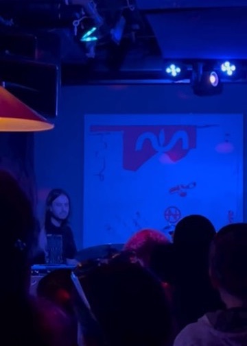 Darksoft's keyboard player on stage in front of a painted backdrop, lit in blue